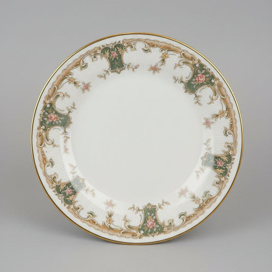 Decorative plate with intricate patterns held in a hand, with a cluttered background.