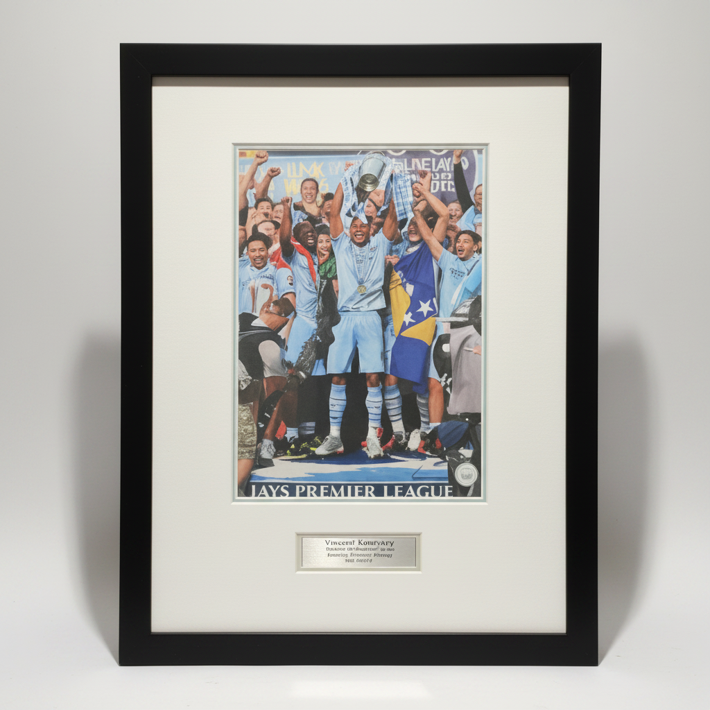 Framed sports memorabilia featuring a printed Manchester City Champions League trophy celebration, mounted with a white mat and black frame, with a small metal plaque below.