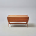 Wooden coffee table on a patterned red rug with a wooden cabinet in the background.