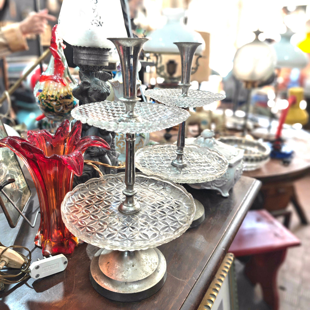 Decorative silver three-tiered stand on a wooden surface with a blurred background
