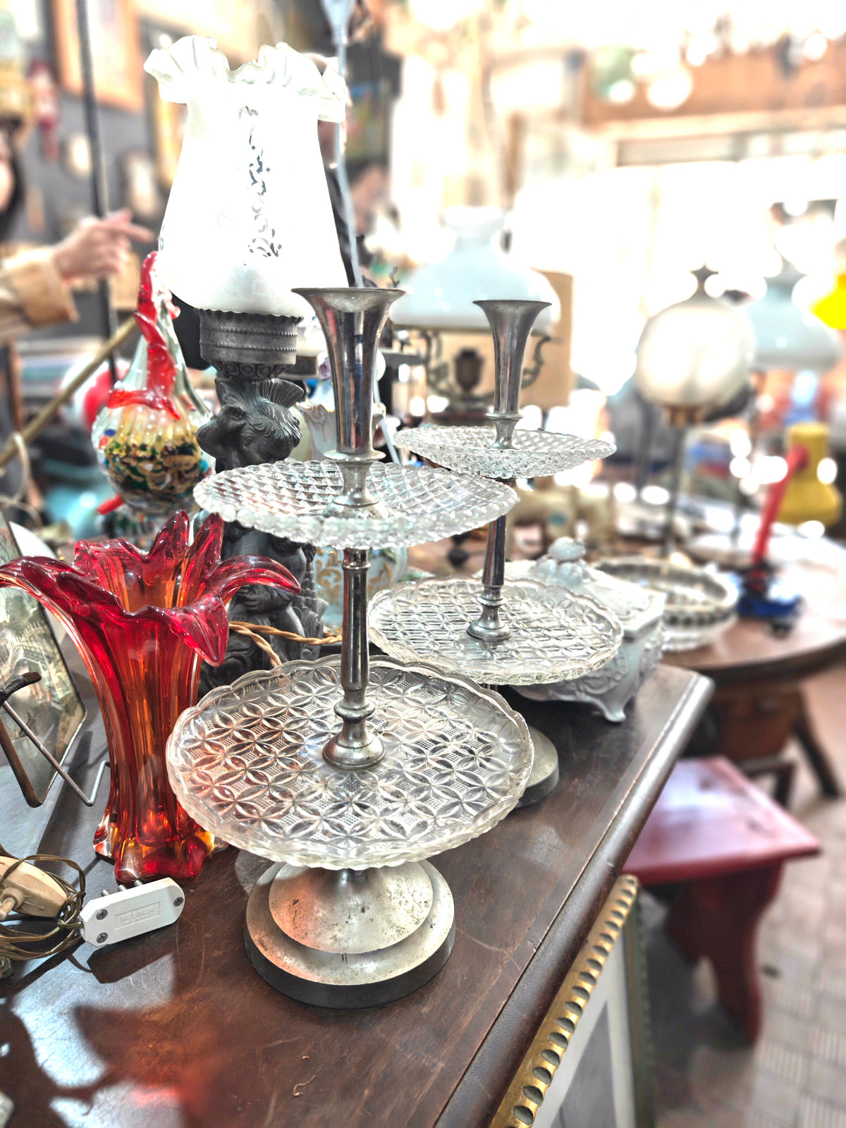 Decorative silver three-tiered stand on a wooden surface with a blurred background