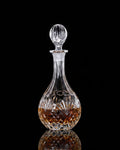 A clear glass decanter with a faceted stopper and a cut crystal pattern, shown on a black background with product details and price text overlaid.