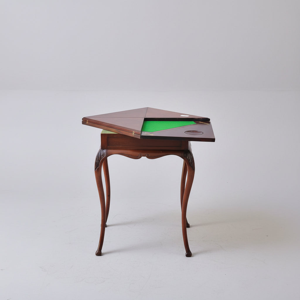 Wooden table with a green top on a red patterned rug