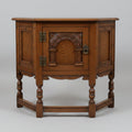 An antique-style dark brown wooden side table with carved decorative panels and turned legs, photographed in a furniture showroom.