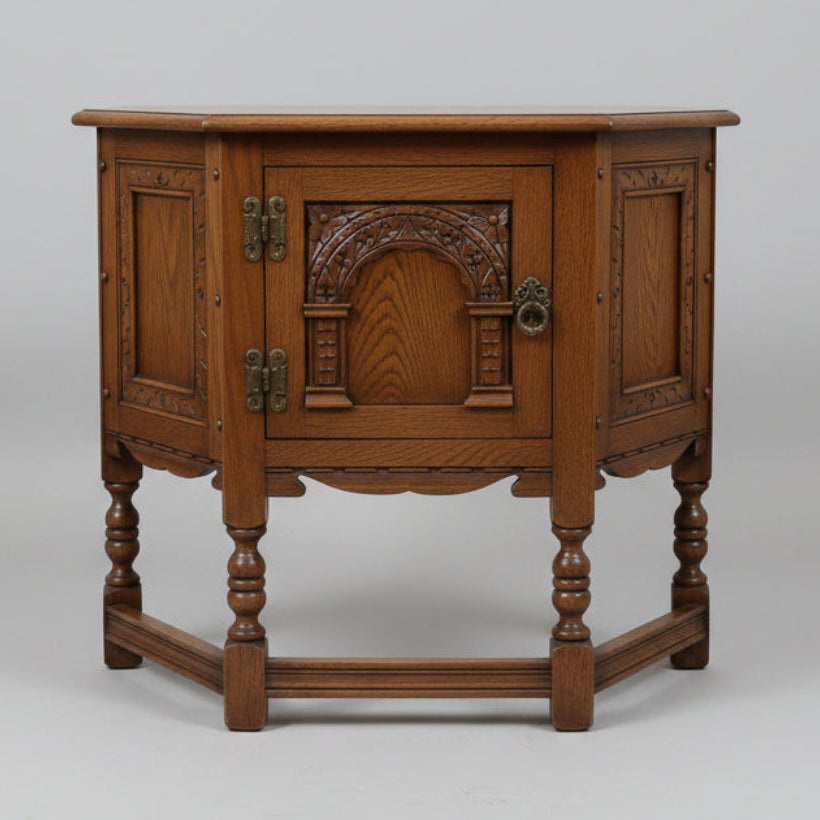 An antique-style dark brown wooden side table with carved decorative panels and turned legs, photographed in a furniture showroom.