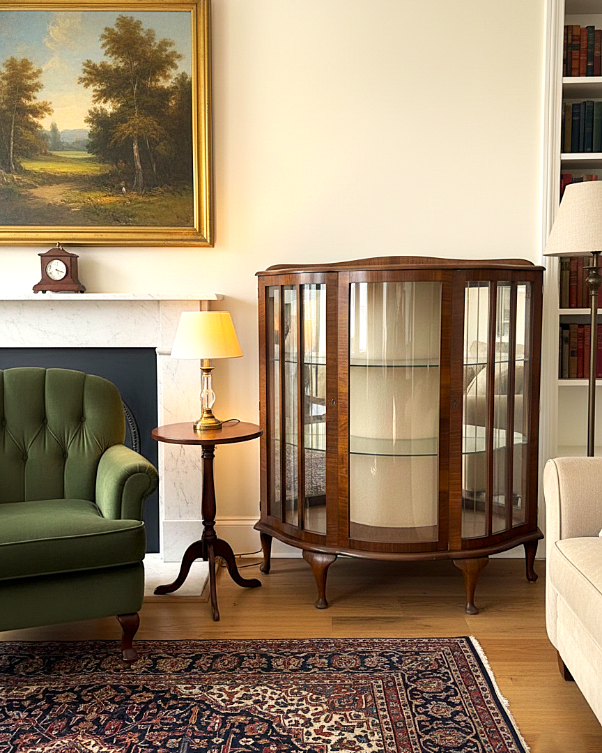 Living room with a green armchair, wooden display cabinet, and a painting on the wall.