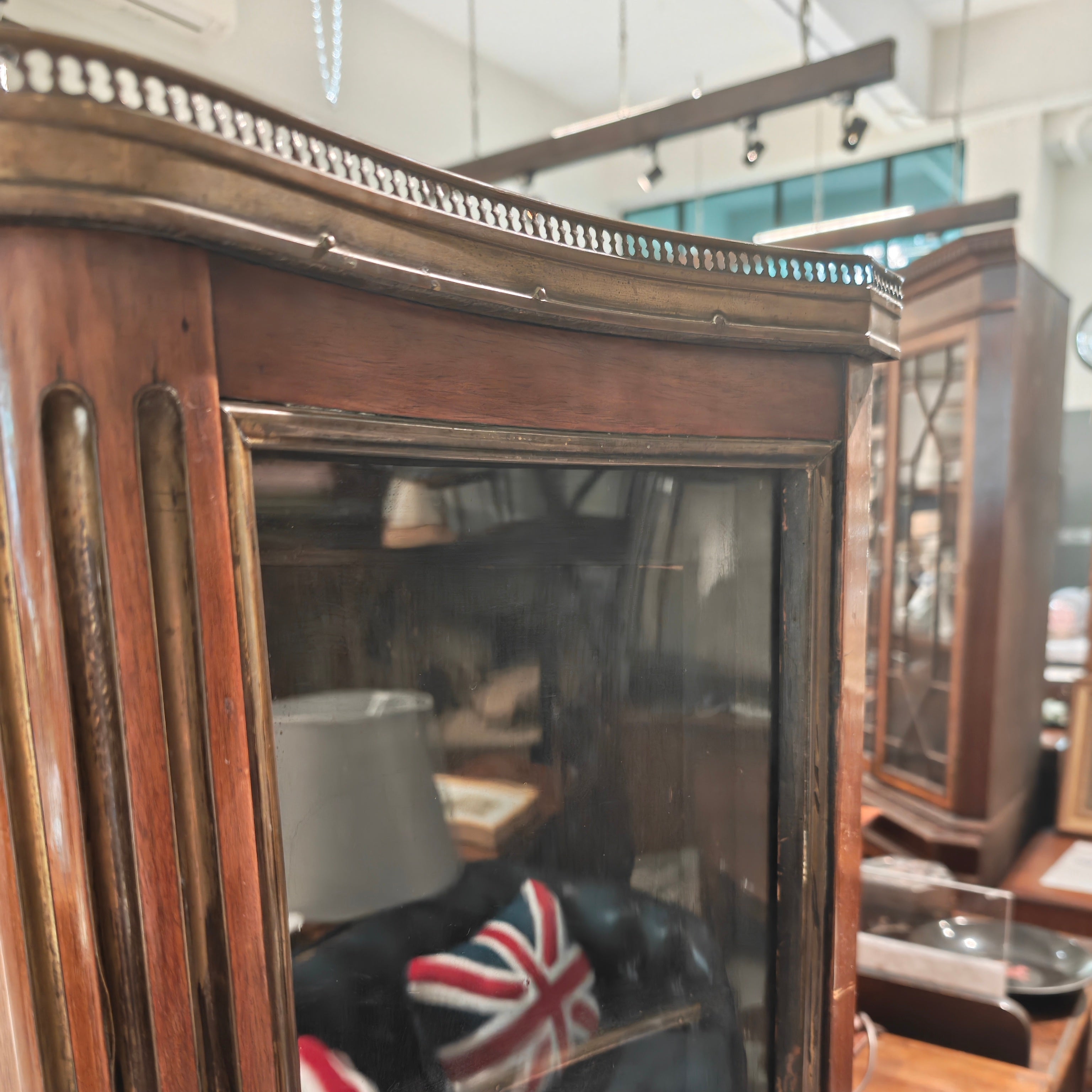 Vintage wooden cabinet with glass doors displaying a Union Jack flag, in an indoor setting.