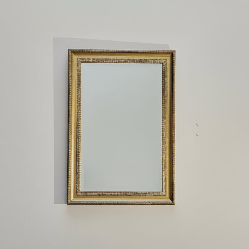 Gold-framed mirror on a plain wall