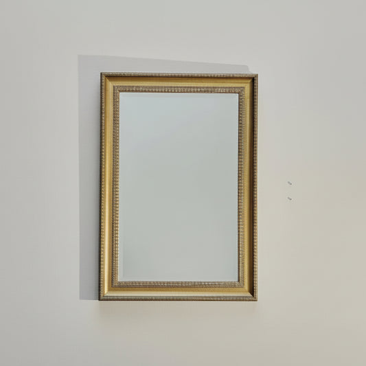 Gold-framed mirror on a plain wall