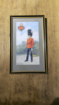 A framed art print depicting a British Royal Guard in red uniform and black bear pelt hat, mounted on a wooden wall.