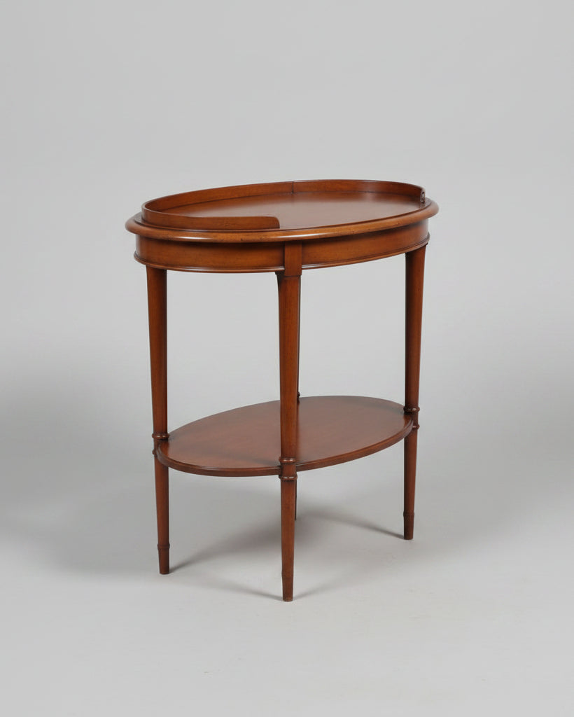 A polished mahogany console table with five drawers, brass handles, and an open lower shelf, shown alongside a matching oval side table on a white background.