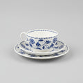 Blue and white floral teacup and saucer set held by a person.