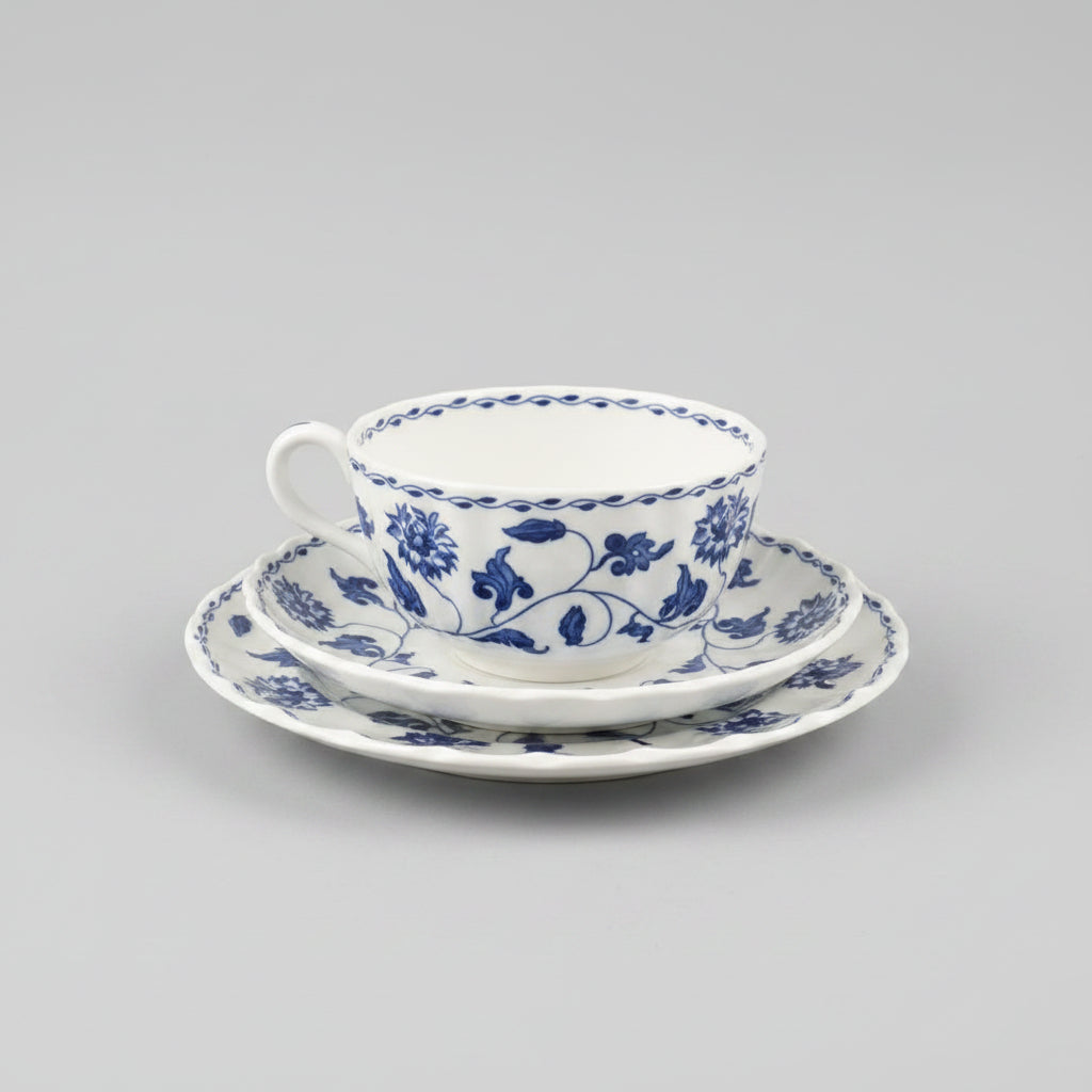Blue and white floral teacup and saucer set held by a person.
