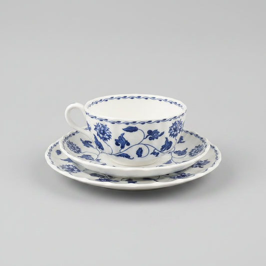 Blue and white floral teacup and saucer set held by a person.