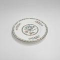 A round white porcelain plate featuring a colorful hand-painted floral border and a central multicolor illustration, displayed on a clean light gray background.