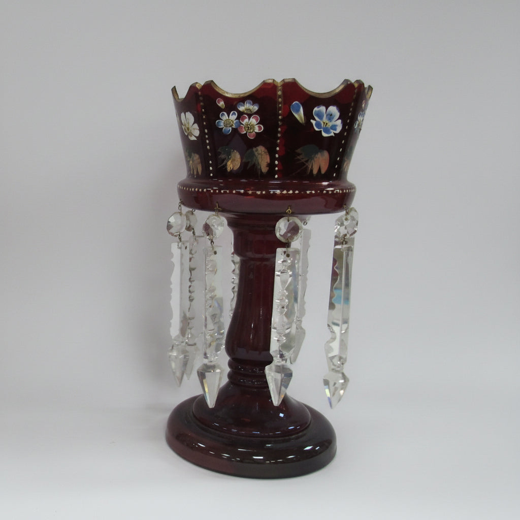 A collection of decorative items on a white studio background, including four   a large dark red crystal candle holder with hanging clear crystals.