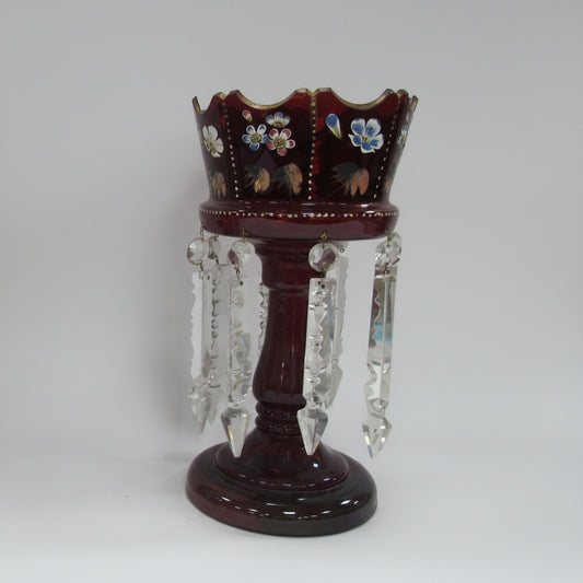 A collection of decorative items on a white studio background, including four   a large dark red crystal candle holder with hanging clear crystals.
