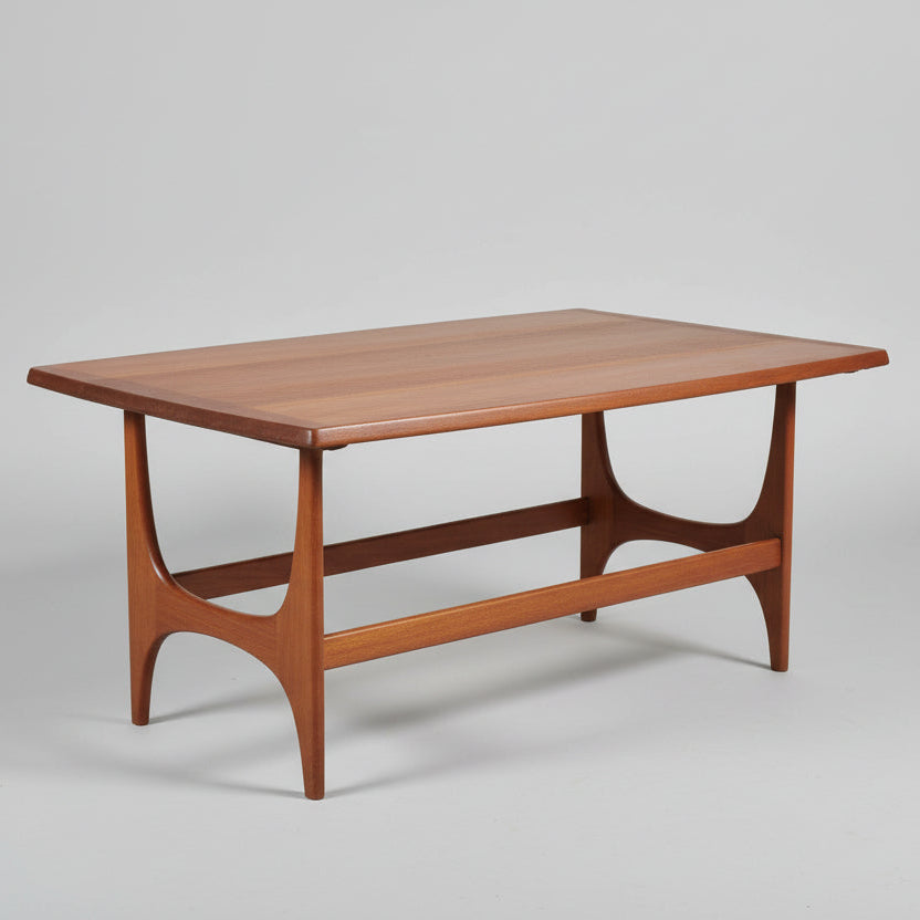 Wooden coffee table with a vase of flowers and decorative items on a red patterned rug.