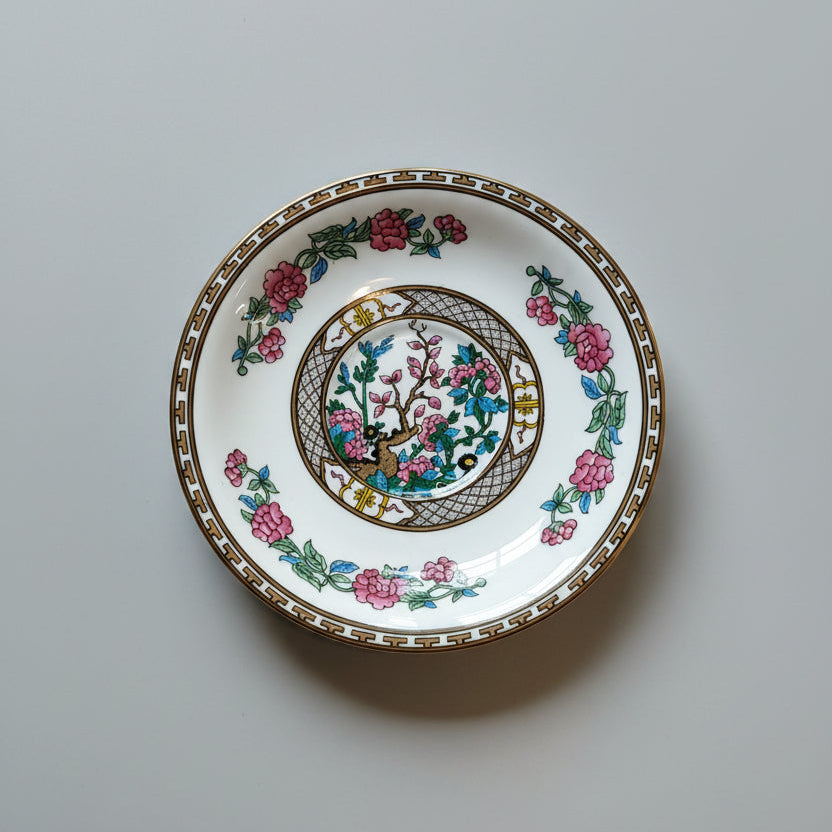 Decorative ceramic plate with floral and bird design on a wooden surface