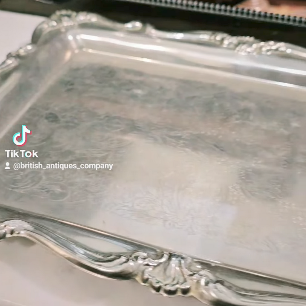 Silver tray with intricate designs on a reflective surface
