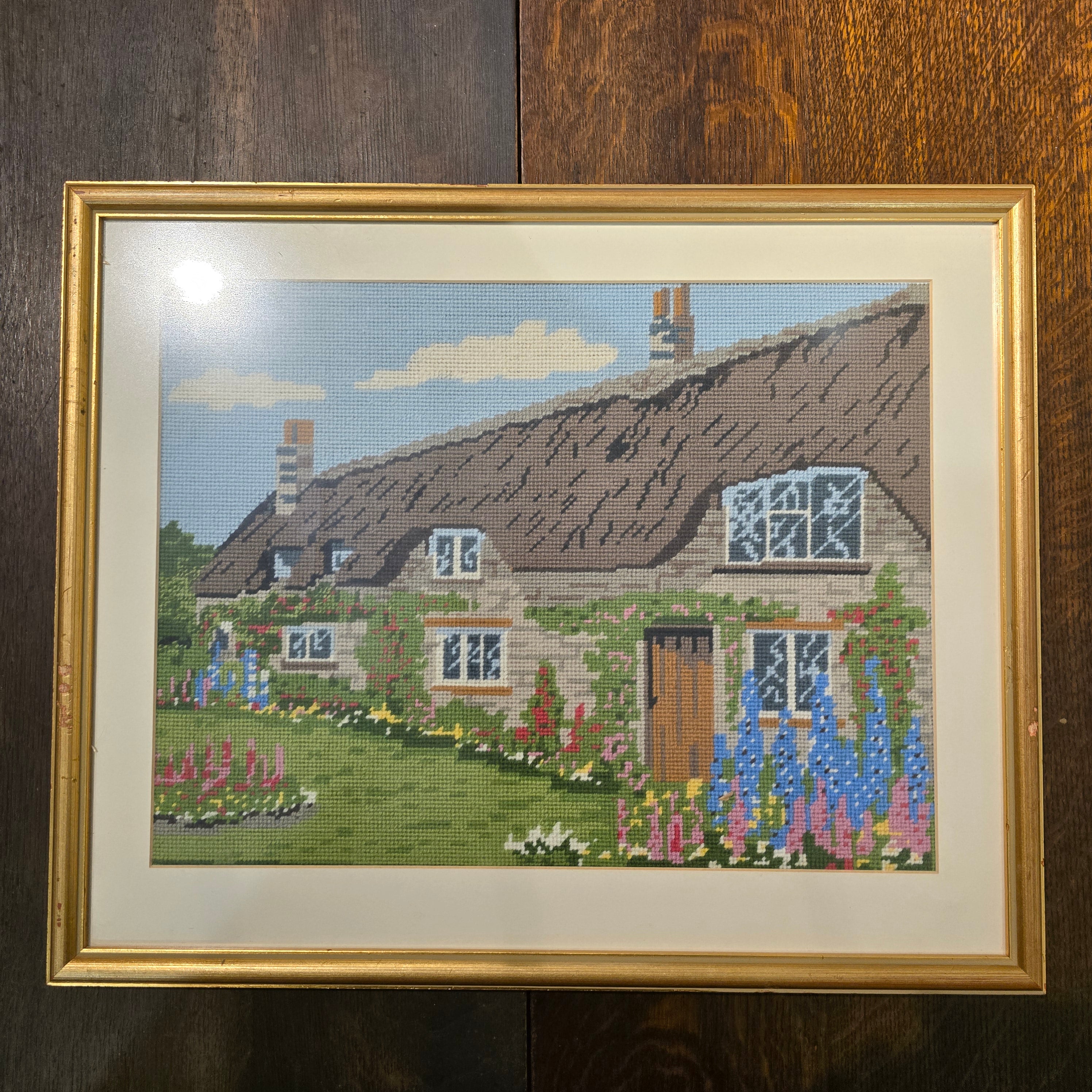 Vintage needle point art work of Thatch roof cottage