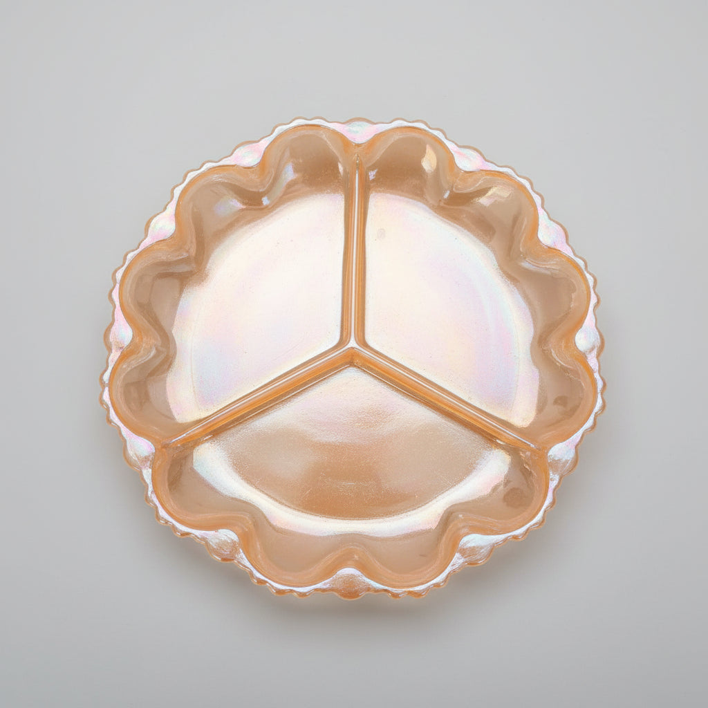 An iridescent orange glass three-piece serving tray with a scalloped rim, shown on a dark wooden tabletop.
