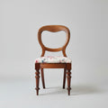 Two wooden chairs with floral cushions on a textured floor, with 'The British Antiques Company' branding.